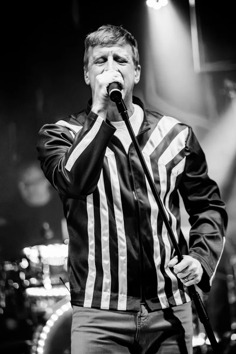 Vocalist in black and white, singing into microphone