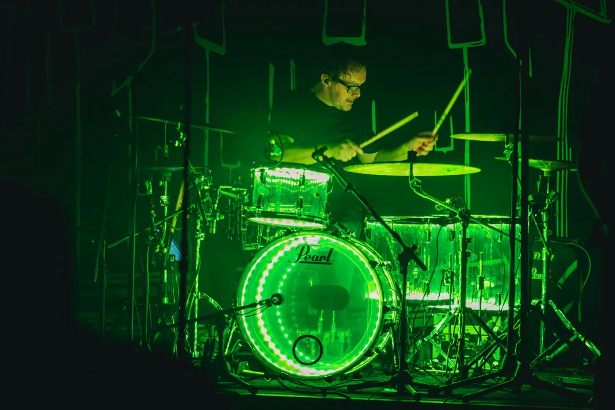 Drummer performing behind green LED drum kit